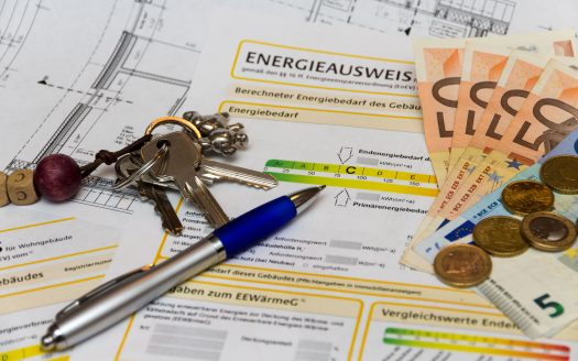 Ein Energieausweis liegt zusammen mit Bargeld und einem Schlüsselbund auf dem Tisch